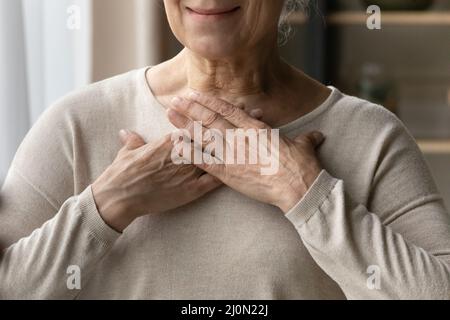 Une femme plus âgée a mis ses mains sur la poitrine en vue rapprochée Banque D'Images