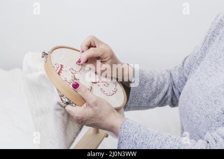 (1)motif de couture croisée de la main de femme sur un cerceau sur fond blanc Banque D'Images