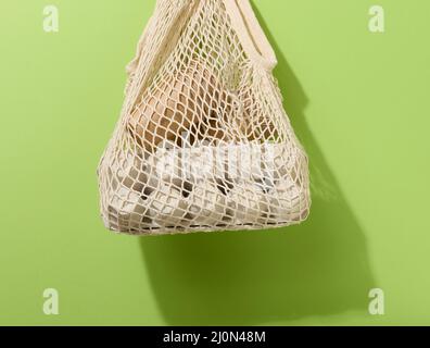 Sac en tissu avec gobelets en papier suspendus sur fond vert. Refus des sacs en plastique Banque D'Images