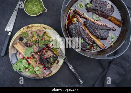 Côtelettes de bœuf braisées traditionnelles à la sauce au vin rouge servies en gros plan dans un four hollandais au design moderne Banque D'Images