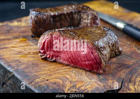 Steak traditionnel de bœuf haché sec frit servi en gros plan dans un vieux panneau rustique en bois Banque D'Images