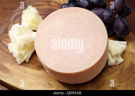 La tete de moine traditionnelle, fromage de montagne des Alpes, offert avec des raisins sur une planche de bois Banque D'Images