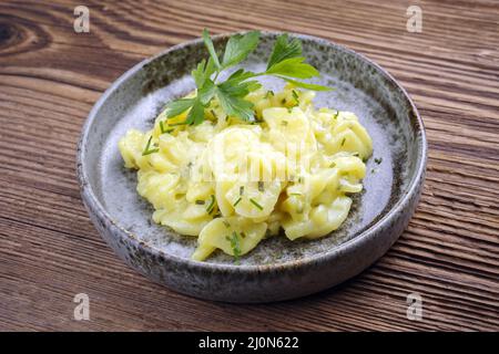 Salade de pommes de terre allemande traditionnelle avec oignon et ciboulette servi comme un gros plan dans un bol design sur un bois rustique Banque D'Images