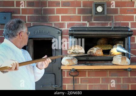 Schwante, Allemagne. 18th mars 2022. Le boulanger principal Volker Rothensee fait sortir les premiers pains de levain du four au début de la saison de cuisson au feu de bois de la boulangerie Plentz Bakery. Deux fois par semaine, à partir d'aujourd'hui, le pain et les gâteaux seront cuits de façon traditionnelle sur le vert du village. Credit: Soeren Stache/dpa-Zentralbild/dpa/Alay Live News Banque D'Images