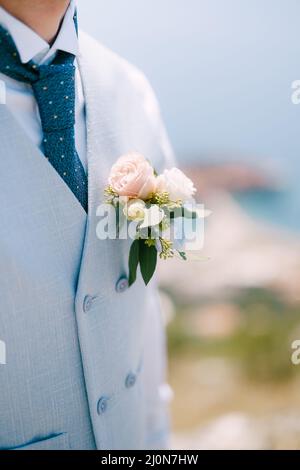 Un homme dans un gilet bleu, une cravate bleue et une boutonnière délicate avec des roses et de l'eucalyptus, gros plan Banque D'Images