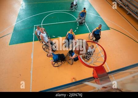 Les vétérans handicapés de guerre ou de travail ont mélangé des équipes de basket-ball de race et d'âge en fauteuil roulant jouant un match d'entraînement dans une salle de sport. Banque D'Images