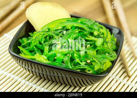 Salade d'algues japonaises wakame au gingembre sur un tapis de bambou Banque D'Images