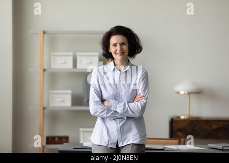 Femme d'affaires confiante et mature debout, les mains repliées Banque D'Images