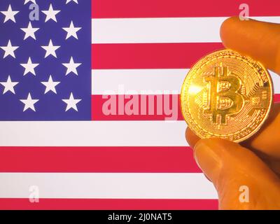 Tenant un Bitcoin d'or physique au-dessus du drapeau américain. Les États-Unis en tant qu'investisseur dans la technologie de la crypto-monnaie et de la blockchain. Contexte financier Banque D'Images