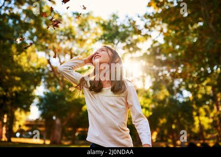 S'autofiltre dans l'air. Photo d'une petite fille heureuse jouant dans l'automne feuilles dehors. Banque D'Images