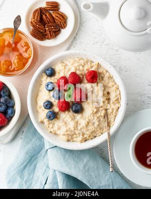 Porridge de flocons d'avoine avec bleuets, framboises, confiture, vertical, vue de dessus. Petit déjeuner avec baies Banque D'Images