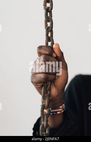 Main d'un Africain noir accroché à une chaîne, symbole de l'esclavage, de l'exploitation et de la privation de liberté Banque D'Images