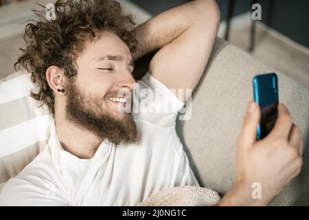 Homme regarde à travers les onglets de son smartphone. Il lit de nouveaux messages dans les réseaux sociaux. Concentration sélective des mains et du téléphone mobile Banque D'Images