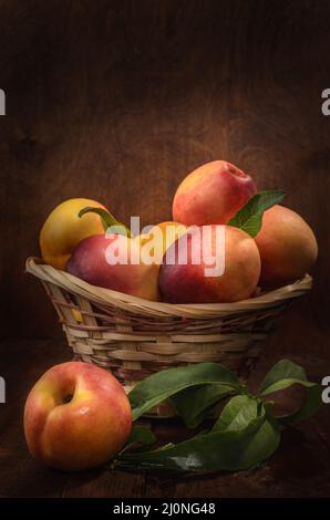 Nectarines dans un panier sur fond de bois sombre dans un style rustique Banque D'Images