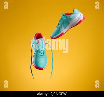 Une paire de sneakers en tissu bleu avec lacets fait levier sur un fond jaune. Chaussures de sport, de jogging Banque D'Images