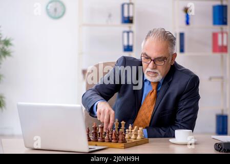 Vieux homme d'affaires jouant aux échecs sur le lieu de travail Banque D'Images