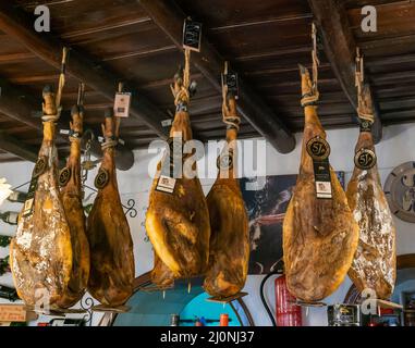 Aracena, Espagne - 16 mars 2022 : pattes de jambon ibérique de Jabago suspendues au plafond dans une auberge traditionnelle de campagne et un restaurant Banque D'Images