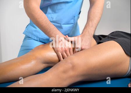 Gros plan d'un thérapeute massant la jambe d'un jeune homme Banque D'Images