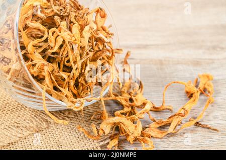 Le cordyceps militaris séché fleur de champignon sur fond de bois. Banque D'Images