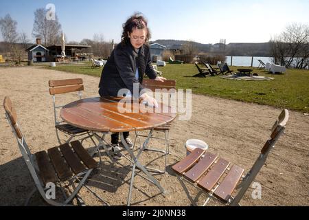 20 mars 2022, Thuringe, Ilmenau: Ashley Quednau, employé de la "Haus am See", prépare les tables dans le café en plein air pour les invités. De nombreuses personnes apprécient le temps et le soleil printaniers de la Thuringe. Photo: Michael Reichel/dpa-Zentralbild/dpa Banque D'Images