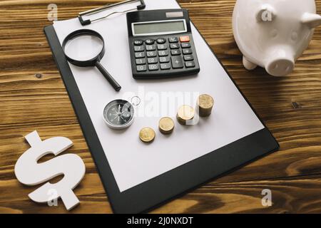 Pile de pièces boussole loupe calculatrice presse-papiers avec signe de dollar piggybank. Haute qualité et résolution pH magnifique Banque D'Images