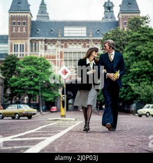 Vintage Amsterdam 1970s, couple élégant de touristes d'âge moyen se promenant en face de Rijksmuseum, Hollande, pays-Bas, Europe, Banque D'Images