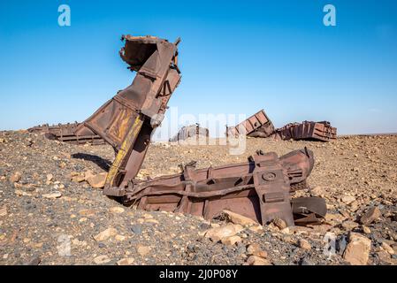 Wagons endommagés sur le sol rocheux près du tunnel de Choum du chemin de fer mauritanien, Mauritanie Banque D'Images