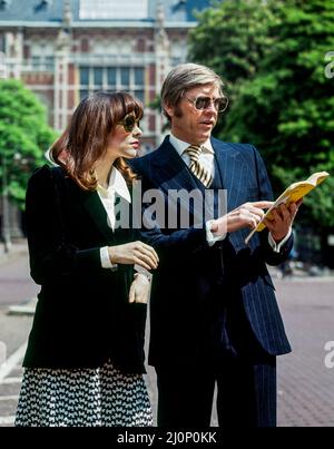 Vintage Amsterdam 1970s, élégant couple de touristes d'âge moyen regardant le guide en face de Rijksmuseum, Hollande, pays-Bas, Europe, Banque D'Images