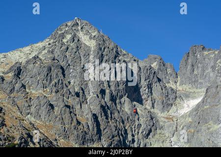 Un téléphérique rouge sur son chemin de Skalnate pleso à Lomnicky pic. Télécabine rouge se déplaçant jusqu'au sommet de Lomnica dans les montagnes de High Tatras. Banque D'Images