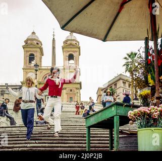 Vintage Rome 1970s, couple exubérant courant sur les marches espagnoles, Piazza di Spagna place, Trinita dei Monti église, Italie, Europe, Banque D'Images