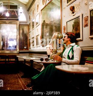 Vintage Rome 1970s, couple élégant ayant un verre et flirtant à l'intérieur de Antico Caffé Greco café, Italie, Europe, Banque D'Images