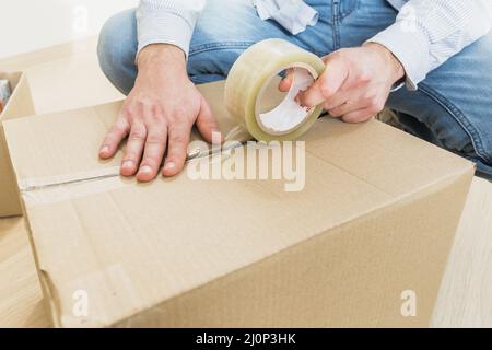 Jeune homme scellant la boîte en carton avec du ruban gros mouvement. Haute qualité et résolution magnifique concept de photo Banque D'Images