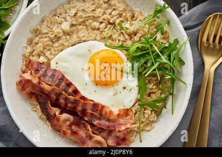 Flocons d'avoine, œufs frits et bacon frit. Équilibre des protéines, des graisses, des glucides. Alimentation équilibrée. Banque D'Images