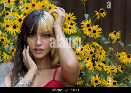 Un charmant modèle Brunette pose dans Un champ de fleurs jaunes tout en appréciant le temps d'été Banque D'Images