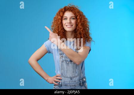 Motivé bonne-regarder confiant redhead maurily fille dungarees se sentent responsabilisés montrant la femme donne tout ce qui pointe vers le haut gauche cor Banque D'Images