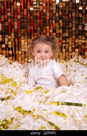 Un garçon et une fille jouent dans une pile de papier blanc et or coupé Banque D'Images