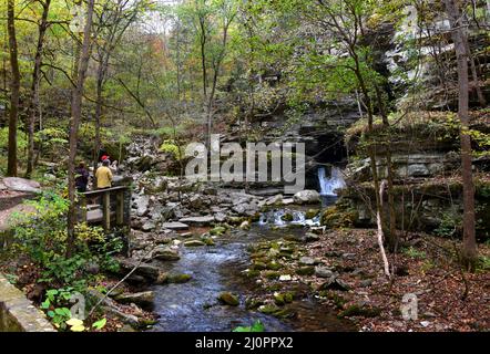 Trois visiteurs admirent la chute d'eau de la caverne de Blanchard Springs, près de Mountain View, Arkansas, sur la plate-forme d'observation. Un homme prend des photos avec son téléphone. Banque D'Images