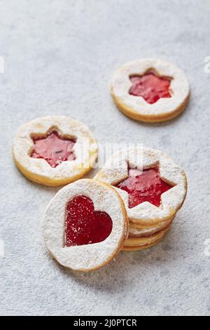 Biscuits de Noël classiques avec confiture de framboises ou de fraises sur fond clair. Banque D'Images