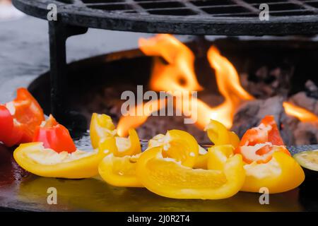 Processus de cuisson des poivrons sur le gril au marché alimentaire de rue - gros plan Banque D'Images