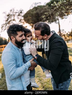 Gay couple d'hommes ayant le plaisir chatouiller leur fille qui rit. Banque D'Images