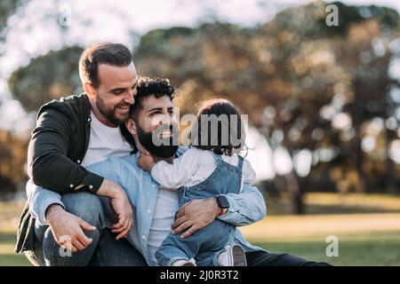 Famille gay masculine embrassant et heureux dans le parc avec leur petite fille Banque D'Images