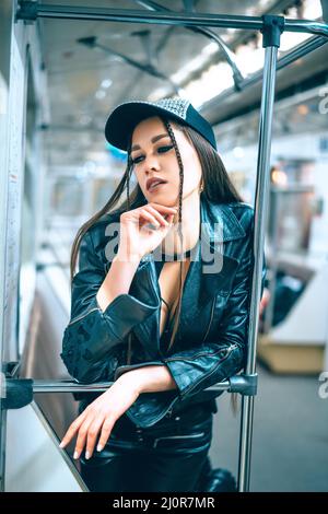 Une femme charmante dans des vêtements tendance et élégants se dresse dans une belle posture dans une voiture de métro. Une fille disco rentre à la maison la nuit d'un p Banque D'Images