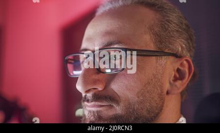 Gros plan extrême d'un employé de bureau d'âge moyen barbu avec des lunettes. Employé fatigué de travailler des heures supplémentaires la nuit. Banque D'Images
