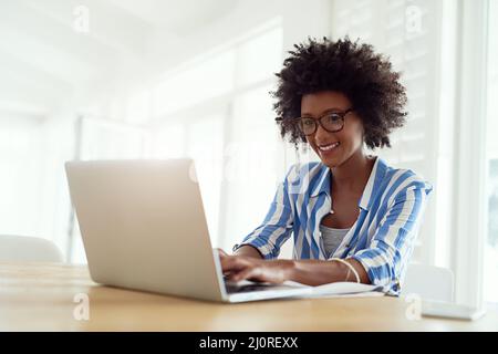 Travailleur indépendant et totalement aimant. Prise de vue rognée d'une jeune femme travaillant sur son ordinateur portable à la maison. Banque D'Images