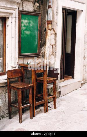 Table haute en bois et deux chaises près du mur d'un petit bar dans la rue Banque D'Images