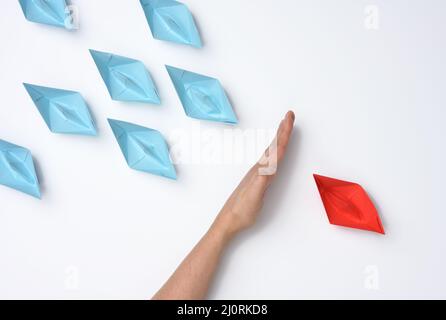 main féminine entre bateaux en papier sur fond blanc, concept de réconciliation des parties, recherche de compromis. Le rôle de la négociato Banque D'Images