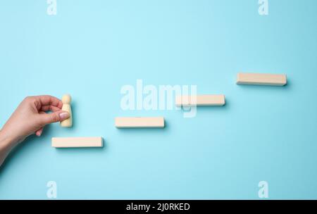 marches en bois et figurine d'un petit homme dans la main d'une femme. Démarrage, démarrage d'une nouvelle entreprise réussie, réalisation des objectifs Banque D'Images