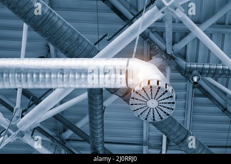 Les tuyaux de ventilation dans l'argent du matériel d'isolation pendant du plafond à l'intérieur de nouveau bâtiment. Banque D'Images