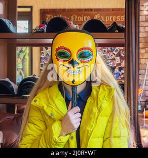 Russie, Kislovodsk 05.11.2021. Une femme tente sur un masque jaune gai avec un motif lumineux dans le style vénitien Banque D'Images