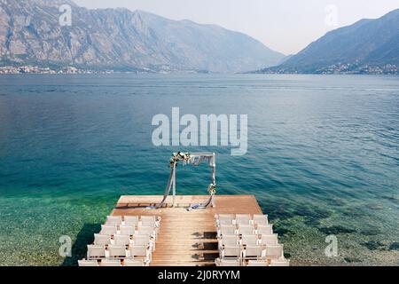 Chaises sur la jetée en bois devant l'arche de mariage sur fond de mer Banque D'Images